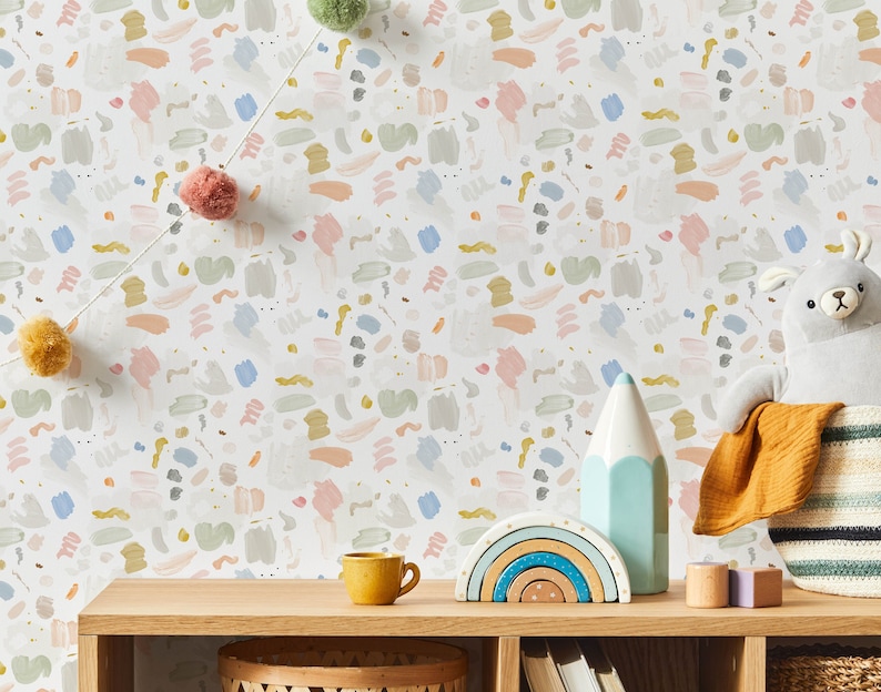 May include: A white wallpaper with a repeating pattern of colorful abstract shapes. The wallpaper is displayed in a room with a wooden shelf, a rainbow-colored wooden toy, a blue pencil, a yellow cup, and a stuffed animal.