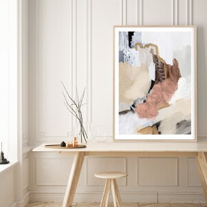K&ouml;nnte beinhalten: Abstrakter Kunstdruck mit wei&szlig;em Hintergrund und braunen, beigefarbenen und rosafarbenen Farbschl&auml;gen. Der Druck ist in einem hellen Holzrahmen gerahmt und h&auml;ngt an einer wei&szlig;en Wand &uuml;ber einem Holztisch.