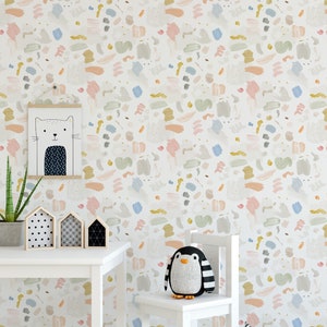 May include: A white table and chair set with a penguin stuffed animal sitting on the chair. The wall behind the furniture is covered in a colorful abstract wallpaper with a pattern of brushstrokes in shades of pink, blue, yellow, and green.
