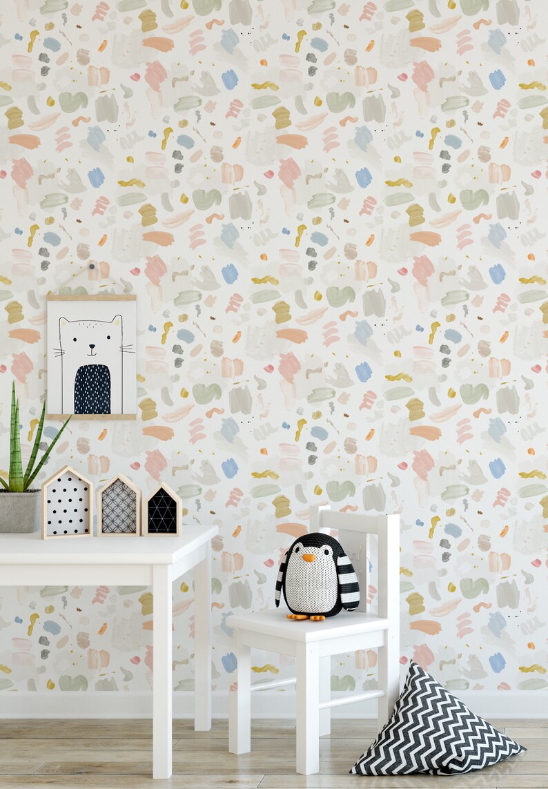 May include: A white table and chair set with a penguin stuffed animal sitting on the chair. The wall behind the furniture is covered in a colorful abstract wallpaper with a pattern of brushstrokes in shades of pink, blue, yellow, and green.