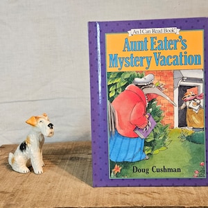 May include: A purple and yellow book titled "Aunt Eater's Mystery Vacation" with an illustration of an anteater and a woman on the cover. The book is part of the "An I Can Read Book" series by Doug Cushman.
