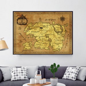 May include: A framed map of a fantasy world, featuring detailed geographical regions and text. The map is in shades of brown and gold, with a black frame. The map is hanging above a gray sofa with decorative pillows.