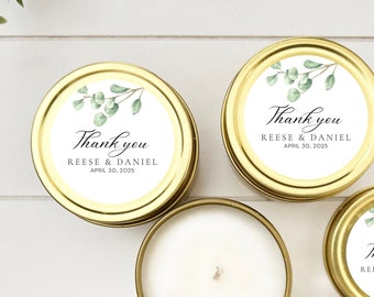 May include: Three gold candle tins with white labels and green eucalyptus illustrations. The labels have the text "Thank you Reese & Daniel April 30, 2025".