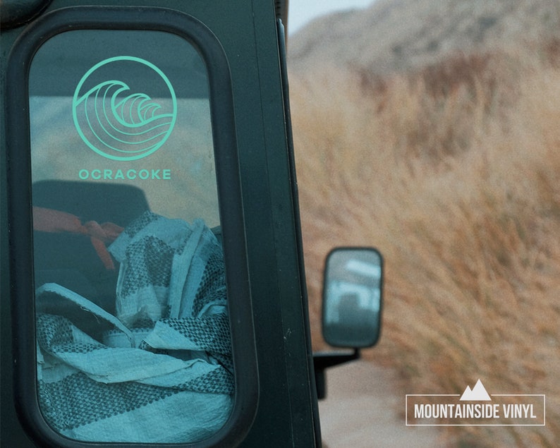 May include: A teal blue wave design sticker with the text "Ocracoke" on a black vehicle window. The sticker is from Mountainside Vinyl.