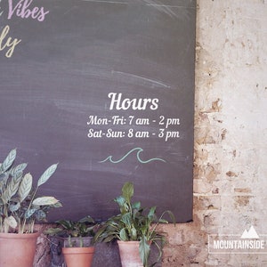 Puede incluir: Un letrero de pizarra con las palabras "Beach Vibes Only" y "Hours" escritas en &eacute;l. El horario de atenci&oacute;n es el siguiente: Lun-Vie: 7 am - 2 pm, S&aacute;b-Dom: 8 am - 3 pm. El letrero est&aacute; colgado en una pared de ladrillo con una peque&ntilde;a planta en una maceta delante de &eacute;l.
