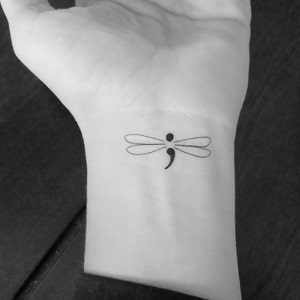 Peut inclure: Tatto de libellule noir et blanc avec un point-virgule au milieu de son corps.