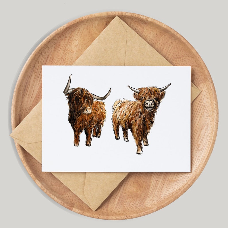Pu&ograve; includere: Un biglietto d'auguri con un'illustrazione ad acquerello di due bovini Highland marroni, noti anche come bovini delle Highlands scozzesi, in piedi uno accanto all'altro.