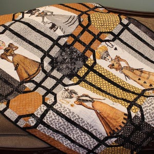 May include: A quilt featuring a repeating pattern of figures in Victorian-style dresses, interspersed with black and gold geometric lattice designs. The fabric displays various textures, including polka dots, paisley, and solid gold panels.