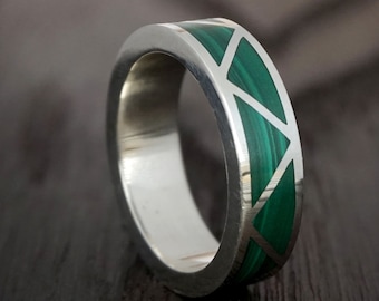 May include: A silver ring with a green malachite inlay. The inlay is in a geometric pattern of triangles.