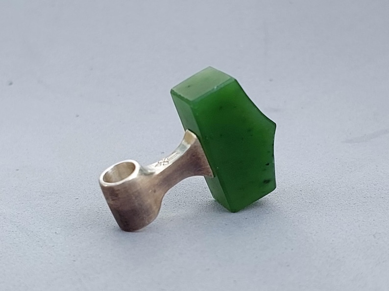 Side view of a handcrafted silver Mjolnir pendant with natural nephrite jade.