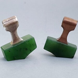 Silver and bronze Mjolnir pendants with hand-carved natural nephrite jade displayed together.