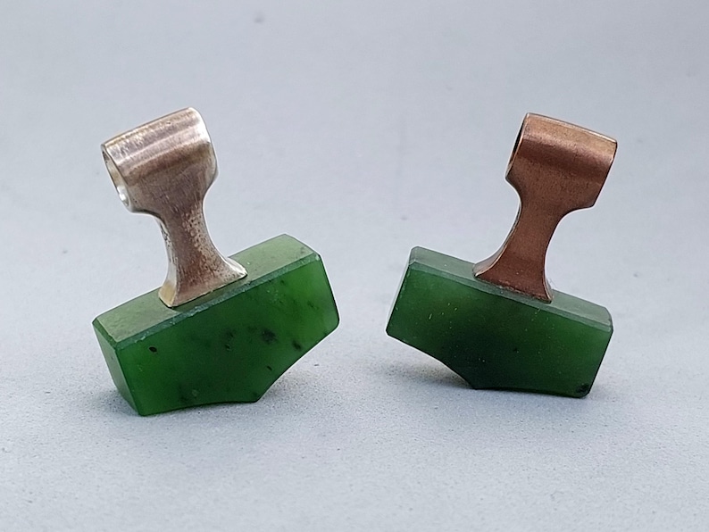 Silver and bronze Mjolnir pendants with hand-carved natural nephrite jade displayed together.