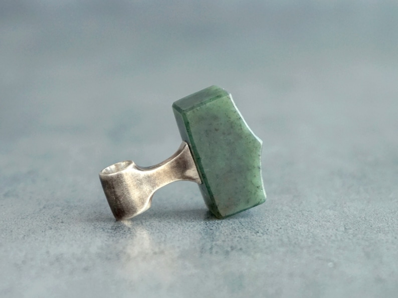 May include: A silver pendant with a green jade stone shaped like a hammer.