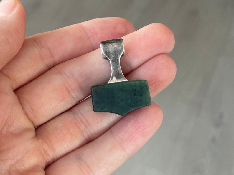 May include: A silver and green Mjolnir pendant, a Norse symbol of Thor's hammer.
