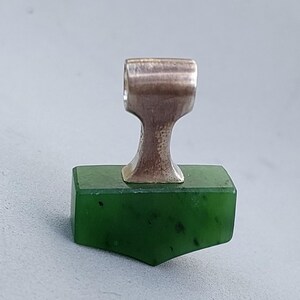Front view of a handcrafted silver Mjolnir pendant with natural nephrite jade.