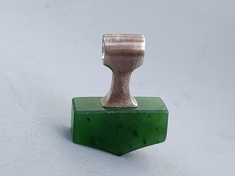 Front view of a handcrafted silver Mjolnir pendant with natural nephrite jade.