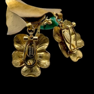 May include: Gold tone flower-shaped earrings with a green stone and a Martha Monteiro tag on the back.