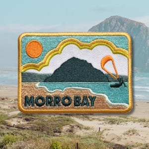 May include: Embroidered patch featuring a coastal scene with the text "MORRO BAY." The design includes a mountain, ocean, sun, and a person kitesurfing. The patch has a gold border and is set against a beach background.