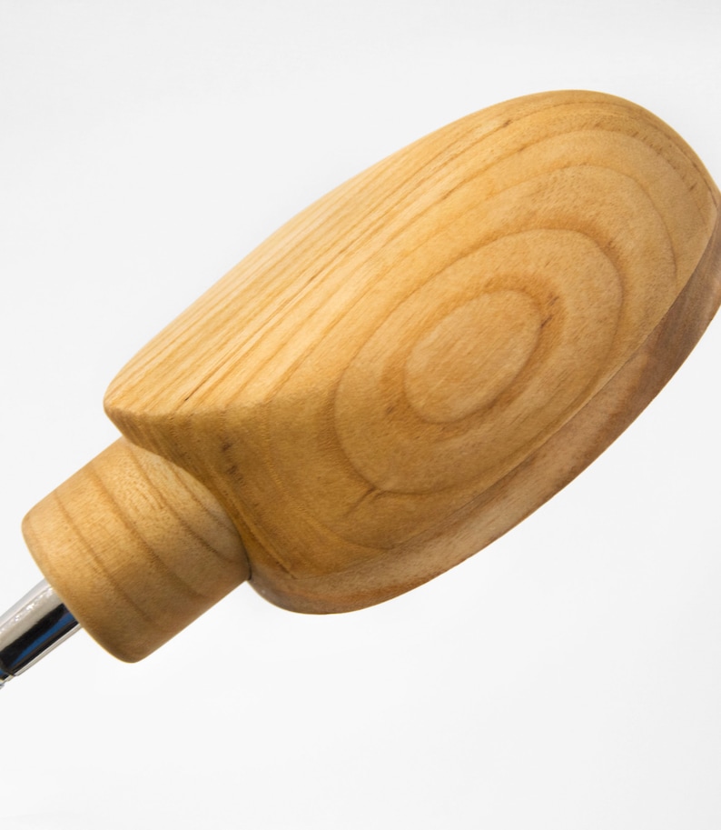 May include: A wooden bottle stopper with a rounded, oval-shaped top. The stopper is made of light brown wood with visible grain patterns.