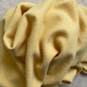 May include: A soft, yellow fabric with a fuzzy texture. The fabric is folded and draped, showing its texture and color.