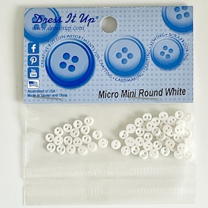 May include: A package of white micro mini round buttons. The package has the text "Dress It Up" and "Micro Mini Round White". The buttons are in a clear plastic bag and on a white background. The package also has social media icons.