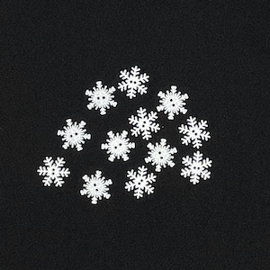 May include: A collection of white snowflake-shaped buttons scattered on a black background. Each button has a detailed snowflake design with six points and a small center hole, perfect for craft projects.
