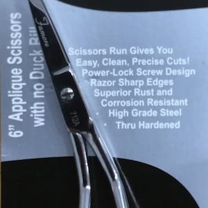 May include: A silver 6-inch applique scissors with a black handle and the text "Famore" on the handle. The scissors are on a white and black background with the text "Famore Cutlery Creative Quality Tools For Creative Minds!" and "Scissors Run Gives You Easy, Clean, Precise Cuts! Power-Lock Screw Design Razor Sharp Edges Superior Rust and Corrosion Resistant High Grade Steel Thru Hardened".