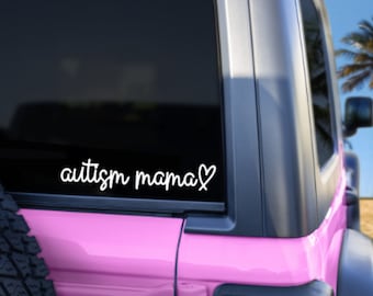 May include: A pink car with a black rear window. The window has a white vinyl decal that says "autism mama" with a heart.