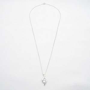 May include: A silver chain necklace with a clear crystal pendant. The pendant is a simple, elegant design with a single crystal set in a silver setting.