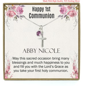 May include: A gift box containing a silver necklace with a cross charm and a purple gemstone. The box features a floral design and the text "Happy 1st Communion" and "Abby Nicole".