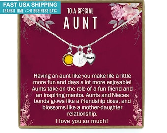 May include: A burgundy gift box with a silver necklace inside. The necklace has a heart charm, a letter charm, and a sun charm. The box has a floral design and the text "To a Special Aunt" and "I love you so much!"