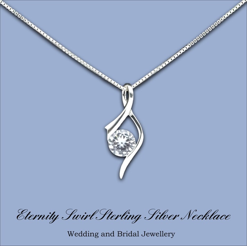 May include: A silver necklace with a swirl design and a clear crystal pendant. The necklace is on a blue background and the text "Eternity Swirl Sterling Silver Necklace" is below the image.  Wedding and Bridal Jewellery.