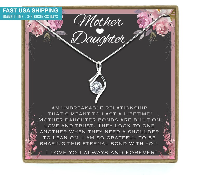 May include: A silver necklace with a clear crystal pendant in a gift box. The box has a floral design and the text "Mother Daughter" with a heart symbol. The text inside the box reads "An unbreakable relationship that's meant to last a lifetime! Mother-daughter bonds are built on love and trust. They look to one another when they need a shoulder to lean on. I am so grateful to be sharing this eternal bond with you. I love you always and forever!"