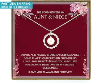 May include: A silver necklace with a pearl pendant in a red box with a floral design. The box has the text "The bond between an aunt & niece" and "AUNTS AND NIECES SHARE AN UNBREAKABLE BOND THAT FLOURISHES ON FRIENDSHIP, LOVE, AND TRUST! HAVING YOU IN MY LIFE HAS ALWAYS BEEN ONE OF MY BIGGEST BLESSINGS. I LOVE YOU ALWAYS AND FOREVER!"