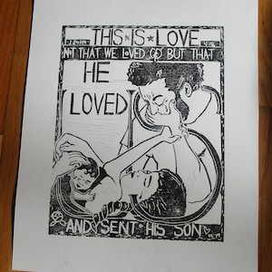 May include: Black and white woodcut print of a couple embracing. The print features the text "This is Love, Not that we loved God but that He Loved and sent His Son."