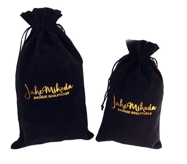 May include: Two black velvet drawstring bags with gold lettering that reads "Jake Mikoda Bronze Sculptures".
