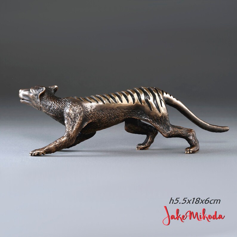 May include: Bronze sculpture of a Tasmanian tiger, also known as a thylacine, in a running pose. The sculpture is 5.5 inches tall, 18 inches long, and 6 inches wide. The sculpture is signed "Jake Mikoda".