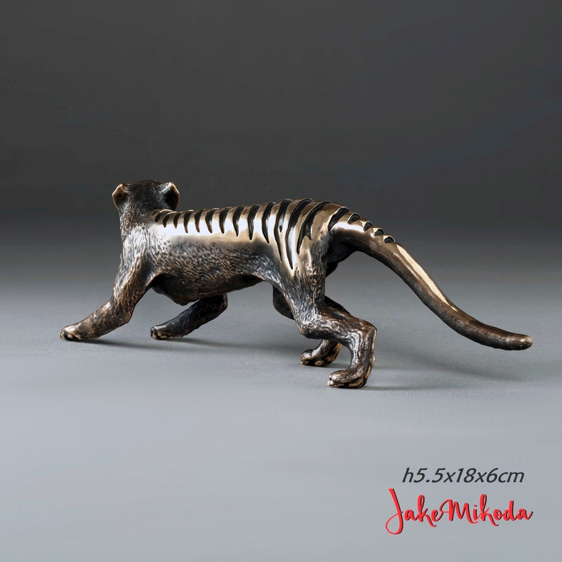 May include: Bronze sculpture of a Tasmanian tiger, also known as a thylacine, in a walking pose. The sculpture is 5.5 inches tall and 18 inches long. The sculpture is by artist Jake Mikoda.