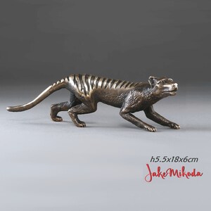 May include: Bronze sculpture of a Tasmanian tiger, also known as a thylacine, in a running pose. The sculpture is 5.5 inches tall, 18 inches long, and 6 inches wide.  The sculpture is by artist Jake Mikoda.