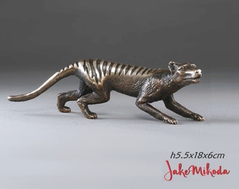 Puede incluir: Escultura de bronce de un tigre de Tasmania, también conocido como tilacino, en una pose de carrera. La escultura mide 5,5 cm de alto, 18 cm de largo y 6 cm de ancho.  La escultura es del artista Jake Mikoda.