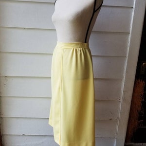 May include: A bright yellow midi skirt with a straight silhouette. The skirt is made of a smooth, lightweight fabric and has a simple, classic design.