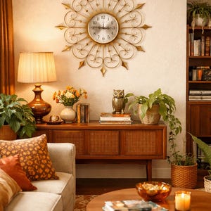 May include: A living room with a mid-century modern aesthetic. A gold-colored sunburst clock hangs above a wooden cabinet. A sofa with patterned pillows, a round coffee table, and a table lamp complete the scene. Plants and decorative items add warmth.