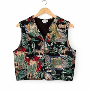 Könnte beinhalten: Gesteppte Weste mit einem Patchwork-Design zum Thema Natur. Die Weste hat einen schwarzen Hintergrund mit Waldszenen, Elchen, Tannenzapfen und Karomustern. Die West ist ärmellos und hat einen V-Ausschnitt.