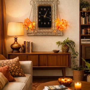 May include: A vintage-style living room with a wooden cabinet, sofa, and coffee table. A decorative clock with a gold frame hangs on the wall, adorned with orange floral accents. A lamp and candles add warm lighting.