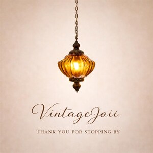 Pu&ograve; includere: Una lampada a sospensione in stile vintage con un paralume in vetro color ambra caldo. La lampada &egrave; sospesa tramite una catena e presenta elementi decorativi in metallo. Il testo "Vintage Joii" e "Thank you for stopping by" sono visibili sotto.