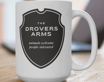May include: White ceramic mug with a black and white graphic of a shield with the text "The Drovers Arms" and the text "animals welcome people tolerated".