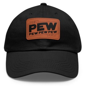 Op de afbeelding: Zwarte baseballpet met een bruin leren patch waarop in zwarte tekst "PEW PEW PEW PEW" staat.