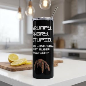 May include: A black cylindrical tumbler with a metal straw and a clear lid. The tumbler features white text that reads: GRUMPY. ANGRY. STUPID. HOW LONG SINCE LAST SLEEP QUESTION? Below the text is a graphic of a brown, multi-legged robotic creature.