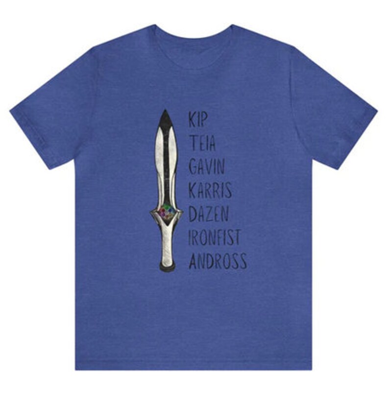 May include: Blue t-shirt featuring a detailed illustration of a dagger with a black blade and silver handle. The names Kip, Teia, Gavin, Karris, Dazen, Ironfist, and Andross are printed vertically next to the dagger.
