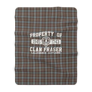 Può includere: Una coperta a quadri marroni, blu e gialli con il testo "PROPERTY OF 1945 CLAN FRASER 1743 LALLYBROCH SCOTLAND" in bianco.